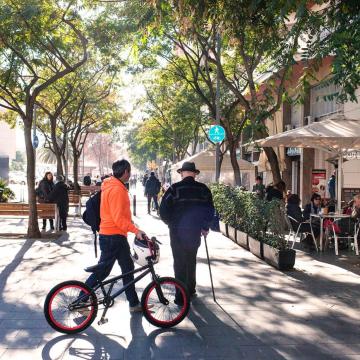 Hombre con bastón y chico paseando en bici por Barcelona